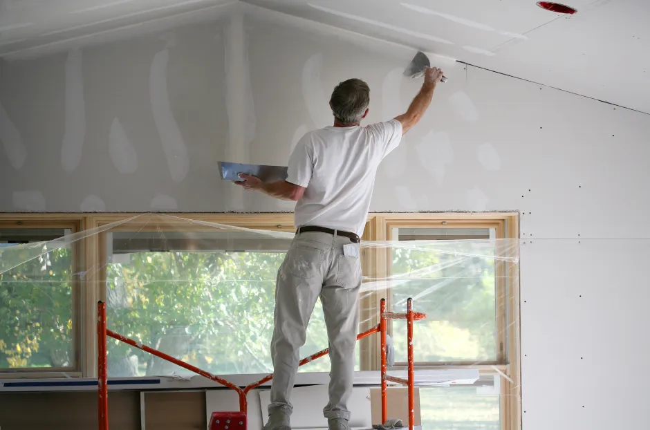 A picture of a man doing sheetrock repairs inside a house in Asheville, NC.
