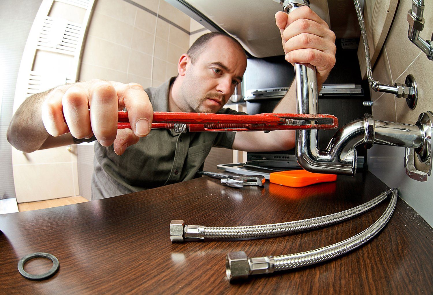 A picture of a man with tools fixing pipes under a sink in Asheville, NC.